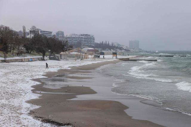 A person walks on the snow-covered Black Sea beach in Odesa on January 23, 2026, amid the Russian invasion in Ukraine. (Photo by Oleksandr GIMANOV / AFP)