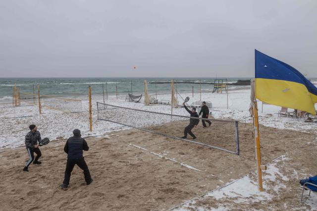 People play padel on the snow-covered Black Sea beach with a Ukrainian flag fluttering in Odesa on January 23, 2026, amid the Russian invasion in Ukraine. (Photo by Oleksandr GIMANOV / AFP)