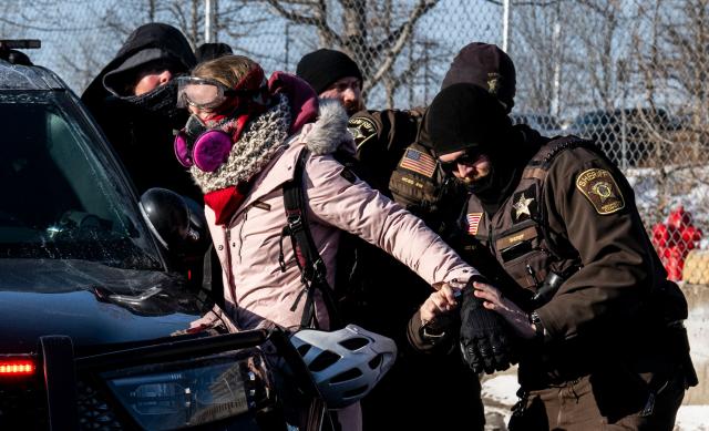 TOPSHOT - An activist is arrested by officers of the Hennepin County Sheriffs Office after some protesters attempted to block the street in front of the Bishop Henry Whipple Federal Building during the "ICE out of Minnesota: Day of Truth and Freedom" protest in Minneapolis, Minnesota on January 23, 2026. The Pentagon has ordered 1,500 US soldiers to prepare for a possible deployment to a state roiled by unrest over an immigration crackdown, US media reported on January 18. The reported preparations come days after President Donald Trump threatened to invoke the Insurrection Act, which enables use of the military to suppress "armed rebellion" or "domestic violence" -- although a day later he said there was no immediate need for it. (Photo by ROBERTO SCHMIDT / AFP)