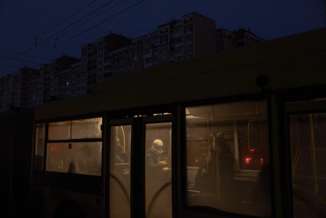 Passengers ride a bus past darkened apartment buildings on a freezing day during a power outage in a residential neighborhood of Kyiv on January 23, 2026, following Russian missile and drone attacks on Ukrainian energy infrastructure amid the Russian invasion in Ukraine. (Photo by Roman PILIPEY / AFP)