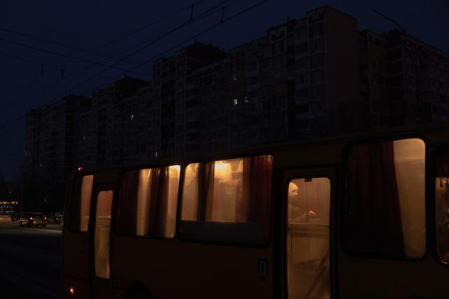 A passenger rides a bus past darkened apartment buildings on a freezing day during a power outage in a residential neighborhood of Kyiv on January 23, 2026, following Russian missile and drone attacks on Ukrainian energy infrastructure amid the Russian invasion in Ukraine. (Photo by Roman PILIPEY / AFP)