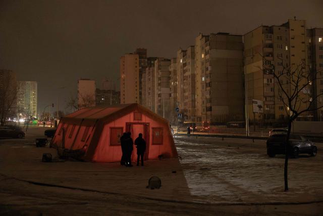 Ukrainian emergency service workers gather next to an emergency service tent set up for those whose homes are without electricity or heating in a residential neighborhood of Kyiv on January 23, 2026, following Russian missile and drone attacks on Ukrainian energy infrastructure amid the Russian invasion in Ukraine. (Photo by Roman PILIPEY / AFP)