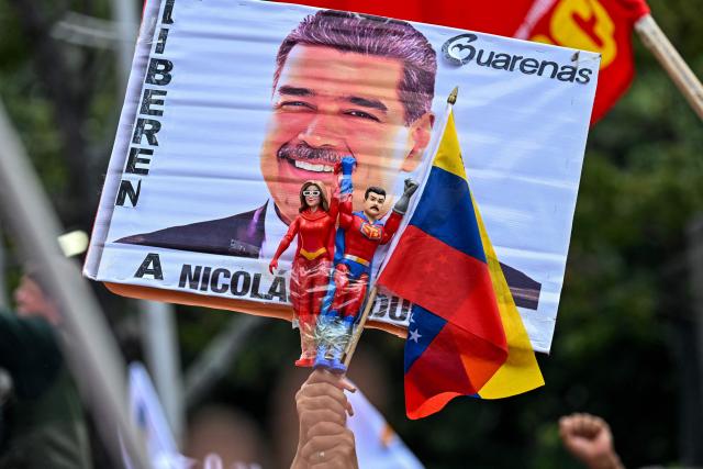 A supporter holds toys depicting ousted Venezuelan President Nicolas Maduro and his wife, Cilia Flores, as the characters named "Super-Bigote" ("Super-Mustache") and "Cilita," during a demonstration calling for the release of him and his wife from a US prison in Caracas on January 23, 2026. Thousands of Nicolas Maduro's supporters marched in Caracas on January 23, calling for the release of the ousted president, as Venezuela marked the 68th anniversary of the fall of military dictatorship. (Photo by Juan BARRETO / AFP)