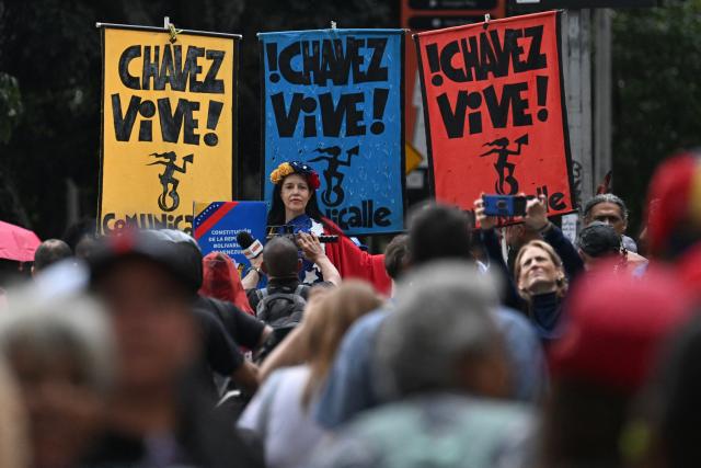 Signs that read in Spanish, 'Chavez lives!' are seen during a demonstration by supporters of ousted Venezuelan President Nicolas Maduro calling for the release of him and his wife from a US prison in Caracas on January 23, 2026. Thousands of Nicolas Maduro's supporters marched in Caracas on January 23, calling for the release of the ousted president, as Venezuela marked the 68th anniversary of the fall of military dictatorship. (Photo by Juan BARRETO / AFP)