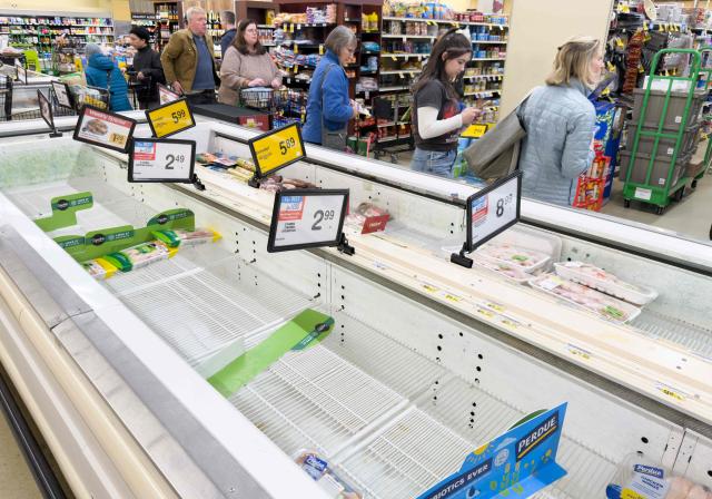 Poultry shelves sit empty as shoppers wait in line to check out ahead of a cold front expected in the area at a supermarket in Arlington, Virginia, on January 23, 2026. A massive winter storm was set to drop a mix of freezing rain and heavy snow on some 160 million Americans starting January 23, threatening to bring dangerously icy conditions. Multiple US states declared states of emergency as meteorologists said the storm would soon begin marching across much of the continental US, covering a wide swath of the country's middle including the Rockies and Plains. (Photo by SAUL LOEB / AFP)