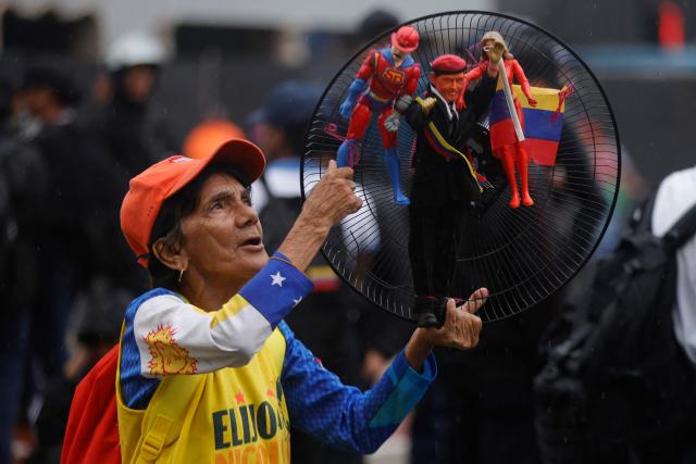 A supporter holds toys depicting late Venezuelan President Hugo Chavez, ousted President Nicolas Maduro as the character named "Super-Bigote" ("Super-Mustache"), and his wife, Cilia Flores, as the character "Cilita," during a demonstration calling for the release of him and his wife from a US prison in Caracas on January 23, 2026. Thousands of Nicolas Maduro's supporters marched in Caracas on January 23, calling for the release of the ousted president, as Venezuela marked the 68th anniversary of the fall of military dictatorship. (Photo by Pedro MATTEY / AFP)