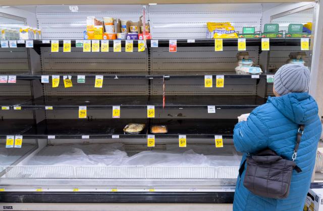 A person shops for eggs on mostly empty shelves as residents stock up on supplies ahead of a cold front expected in the area in Arlington, Virginia, on January 23, 2026. A massive winter storm was set to drop a mix of freezing rain and heavy snow on some 160 million Americans starting January 23, threatening to bring dangerously icy conditions. Multiple US states declared states of emergency as meteorologists said the storm would soon begin marching across much of the continental US, covering a wide swath of the country's middle including the Rockies and Plains. (Photo by SAUL LOEB / AFP)