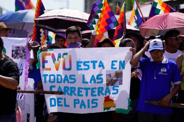 A man shows a sign that reads in Spanish, "Evo is on every road in the country," during the celebrations marking the Day of the Plurinational State, in the town of Lauca Ene, Shinaota, Bolivia, on January 23, 2026. (Photo by Pablo Rivera / AFP)