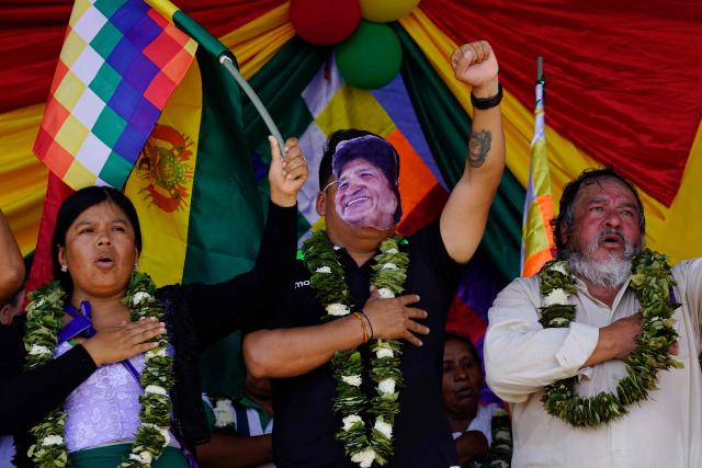 A man wearing a mask depicting former Bolivian President Evo Morales gestures during the celebrations marking the Day of the Plurinational State, in Shinaota, Bolivia, on January 23, 2026. (Photo by Pablo Rivera / AFP)