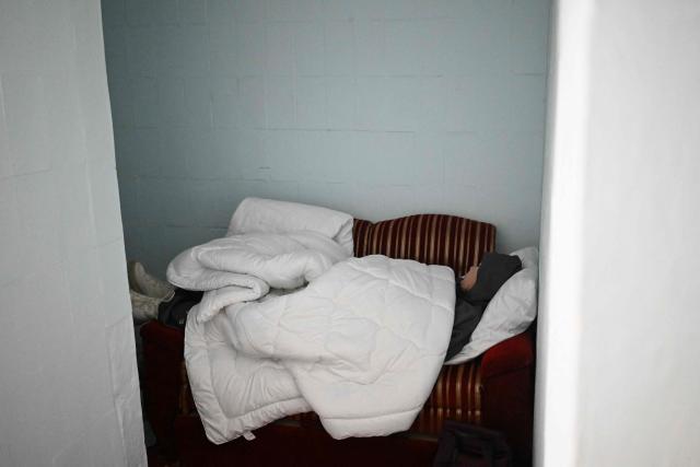 A person lies on the sofa in the hotel's underground shelter during an air attack in Kyiv early on January 24, 2026, amid the Russian invasion of Ukraine. (Photo by Sergei GAPON / AFP)