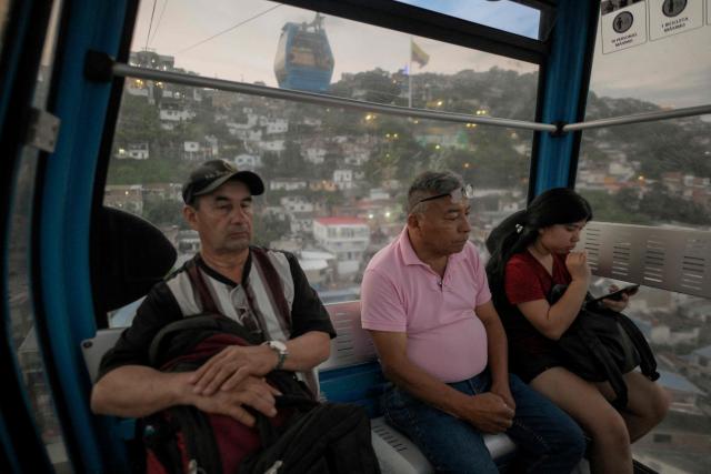 People ride on a cable car from the "MIO Cable" public transport system as they cross the Siloe neighborhood in Cali, Colombia, on January 23, 2026. Santiago de Cali, often referred to as Cali, is the capital of Colombia's Valle del Cauca department and the country's third-largest city. (Photo by JOAQUIN SARMIENTO / AFP)