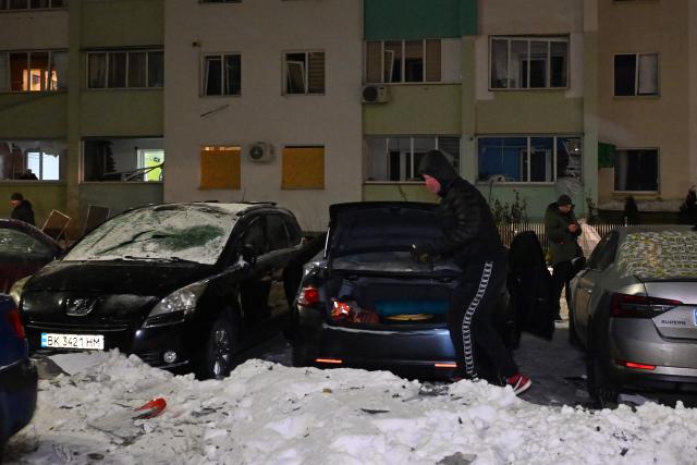 A local resident inspects his car in front of a damaged  residential building following an air attack in Kharkiv on January 24, 2026, amid the Russian invasion of Ukraine. Russian strikes killed one person and injured 23 others in Ukraine's capital and the northeastern city of Kharkiv overnight, authorities said early on January 24, 2026. (Photo by SERGEY BOBOK / AFP)