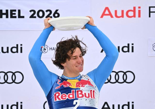 Winner Italy's Giovanni Franzoni celebrates on the podium with his trophy after the Men's Downhill event of the FIS Alpine Skiing World Cup in Kitzbuhel, Austria, on January 24, 2026. (Photo by Joe Klamar / AFP)
