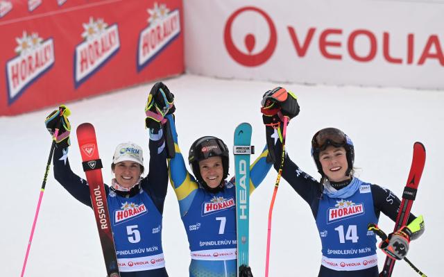 Winner Sweden's Sara Hector (C) celebrates with second-placed US' Paula Moltzan (L) and third-placed US' Mikaela Shiffrin (R) in the finishing area after competing in the second run of the Women's Giant Slalom event of FIS Alpine Skiing World Cup in Spindleruv Mlyn on January 24, 2026. (Photo by Michal Cizek / AFP)