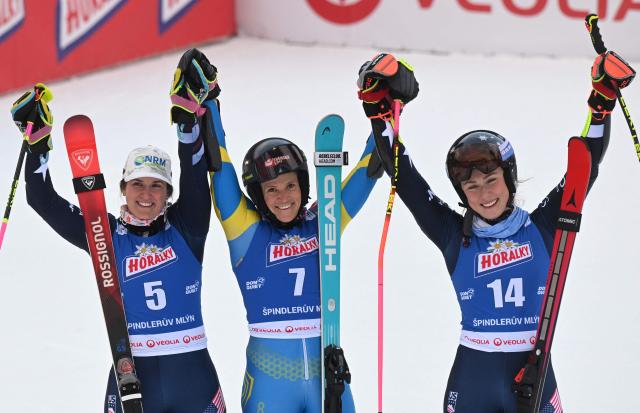 Winner Sweden's Sara Hector (C) celebrates with second-placed US' Paula Moltzan (L) and third-placed US' Mikaela Shiffrin (R) in the finishing area after competing in the second run of the Women's Giant Slalom event of FIS Alpine Skiing World Cup in Spindleruv Mlyn on January 24, 2026. (Photo by Michal Cizek / AFP)