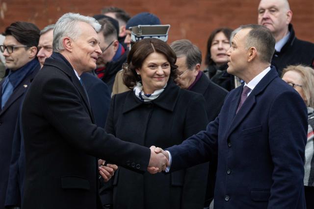 Lithuania's President Gitanas Nauseda (L) and Poland's President Karol Nawrocki (R) shake hands as Diana Nausediene (C) looks on during ceremonies marking the 163th anniversary of January Uprising - a Polish-led insurrection in 1863–1864 against the Russian Empire, at the Execution Gate at the 19th century Warsaw Citadel on January 24, 2025. (Photo by Wojtek RADWANSKI / AFP)
