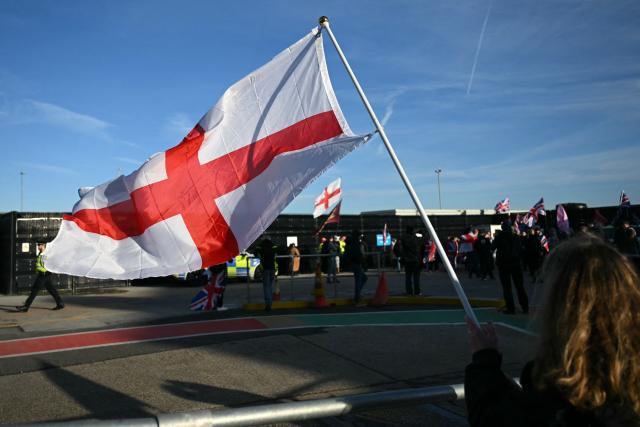People wave flags as right wing protesters gather outside a processing centre for migrants in Dover on the south east coast of England on January 24, 2026. (Photo by JUSTIN TALLIS / AFP)