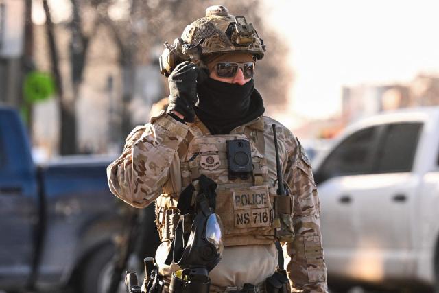 A US Customs and Border Patrol agent looks on as demonstators gather near the site of where state and local authorities say a man was shot by federal agents earlier in the morning in Minneapolis, Minnesota, on January 24, 2026. Minnesota Governor Tim Walz said Saturday that federal agents deployed in Minneapolis as part of a sweeping immigration crackdown had carried out "another horrific shooting," less than three weeks after the fatal shooting of Renee Good. (Photo by ROBERTO SCHMIDT / AFP)