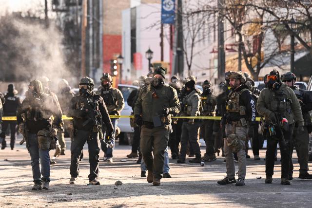 Federal agents stand near police tape as demonstators gather near the site of where state and local authorities say a man was shot by federal agents earlier in the morning in Minneapolis, Minnesota, on January 24, 2026. Minnesota Governor Tim Walz said Saturday that federal agents deployed in Minneapolis as part of a sweeping immigration crackdown had carried out "another horrific shooting," less than three weeks after the fatal shooting of Renee Good. (Photo by ROBERTO SCHMIDT / AFP)