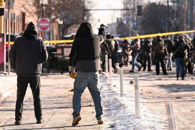 Protestors gesture toward federal agents as demonstators gather near the site of where state and local authorities say a man was shot by federal agents earlier in the morning in Minneapolis, Minnesota, on January 24, 2026. Minnesota Governor Tim Walz said Saturday that federal agents deployed in Minneapolis as part of a sweeping immigration crackdown had carried out "another horrific shooting," less than three weeks after the fatal shooting of Renee Good. (Photo by ROBERTO SCHMIDT / AFP)