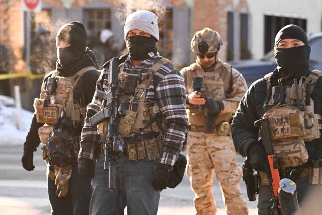Federal agents look on as demonstators gather near the site of where state and local authorities say a man was shot by federal agents earlier in the morning in Minneapolis, Minnesota, on January 24, 2026. Minnesota Governor Tim Walz said Saturday that federal agents deployed in Minneapolis as part of a sweeping immigration crackdown had carried out "another horrific shooting," less than three weeks after the fatal shooting of Renee Good. (Photo by ROBERTO SCHMIDT / AFP)