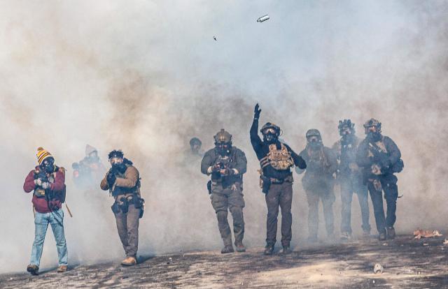 A federal agent lobs a teargas canister towards protesters as agents advance through clouds of tear gas during clashes following the fatal shooting of a protester earlier in the day, on January 24, 2026 in Minneapolis, Minnesota. Federal immigration agents shot dead a man in Minneapolis on Saturday, officials said -- the second fatal shooting of a civilian in the city, sparking fresh protests and outrage from state officials. The death came less than three weeks after US citizen Renee Good was shot and killed by an Immigration and Customs Enforcement officer involved in sweeps to round up undocumented migrants. (Photo by Kerem YUCEL / AFP)