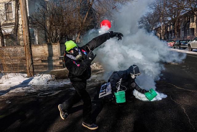 A protester throws an object back toward federal agents while another attempts to extinguish a tear gas canister as smoke fills a residential street during clashes following the fatal shooting of a demonstrator earlier in the day, on January 24, 2026 in Minneapolis, Minnesota. Federal immigration agents shot dead a man in Minneapolis on Saturday, officials said -- the second fatal shooting of a civilian in the city, sparking fresh protests and outrage from state officials. The death came less than three weeks after US citizen Renee Good was shot and killed by an Immigration and Customs Enforcement officer involved in sweeps to round up undocumented migrants. (Photo by Kerem YUCEL / AFP)