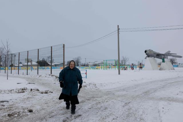 A woman walks down a snow-covered street in the village Verbki, Dnipropetrovsk region, on January 24, 2026, amid the Russian invasion of Ukraine. (Photo by Tetiana DZHAFAROVA / AFP)