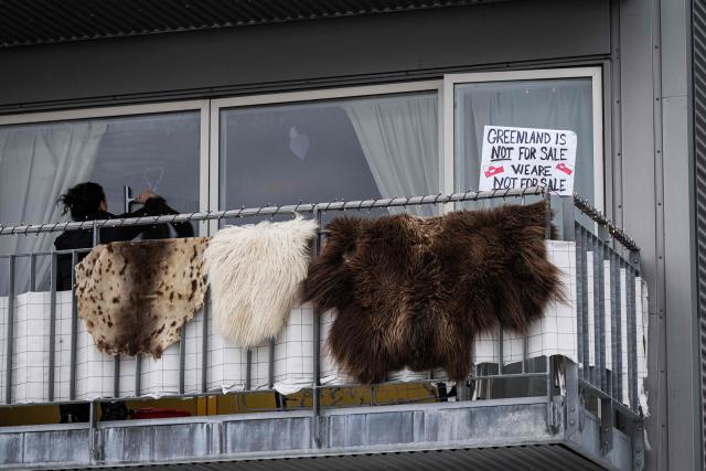 Animal skins hang from a balcony railing as a sign reading “Greenland is not for sale. We are not for sale” is displayed in a window of an apartment building in Nuuk, Greenland, on January 24, 2026. (Photo by Jonathan NACKSTRAND / AFP)