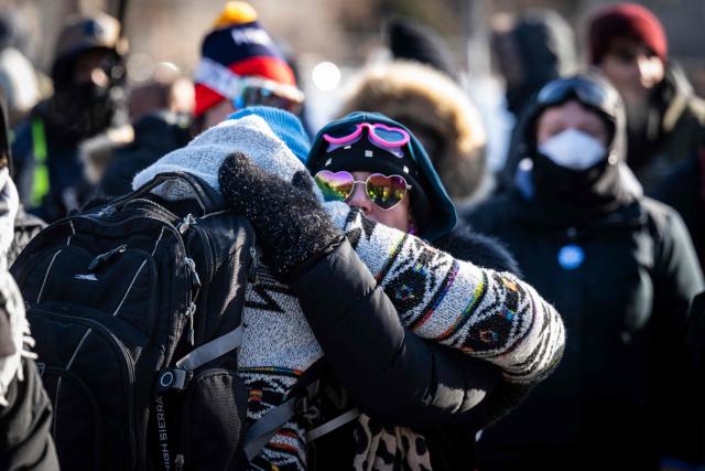 Two residents of the city comfort each other at a makeshift memorial near where a man was shot and killed by federal immigration agents in Minneapolis, Minnesota, on January 24, 2026. Federal immigration agents shot dead a man in Minneapolis on Saturday, officials said -- the second fatal shooting of a civilian in the city, sparking fresh protests and outrage from state officials. The death came less than three weeks after US citizen Renee Good was shot and killed by an Immigration and Customs Enforcement officer involved in sweeps to round up undocumented migrants. (Photo by ROBERTO SCHMIDT / AFP)