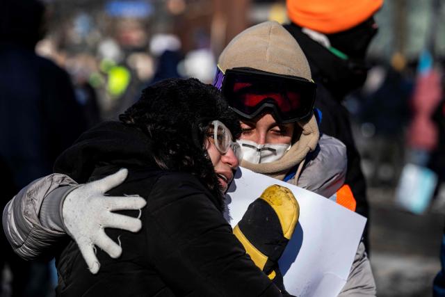 Two residents of the city comfort each other at a makeshift memorial near where a man was shot and killed by federal immigration agents in Minneapolis, Minnesota, on January 24, 2026. Federal immigration agents shot dead a man in Minneapolis on Saturday, officials said -- the second fatal shooting of a civilian in the city, sparking fresh protests and outrage from state officials. The death came less than three weeks after US citizen Renee Good was shot and killed by an Immigration and Customs Enforcement officer involved in sweeps to round up undocumented migrants. (Photo by ROBERTO SCHMIDT / AFP)