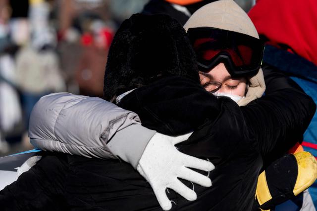 Two residents of the city comfort each other at a makeshift memorial near where a man was shot and killed by federal immigration agents in Minneapolis, Minnesota, on January 24, 2026. Federal immigration agents shot dead a man in Minneapolis on Saturday, officials said -- the second fatal shooting of a civilian in the city, sparking fresh protests and outrage from state officials. The death came less than three weeks after US citizen Renee Good was shot and killed by an Immigration and Customs Enforcement officer involved in sweeps to round up undocumented migrants. (Photo by ROBERTO SCHMIDT / AFP)