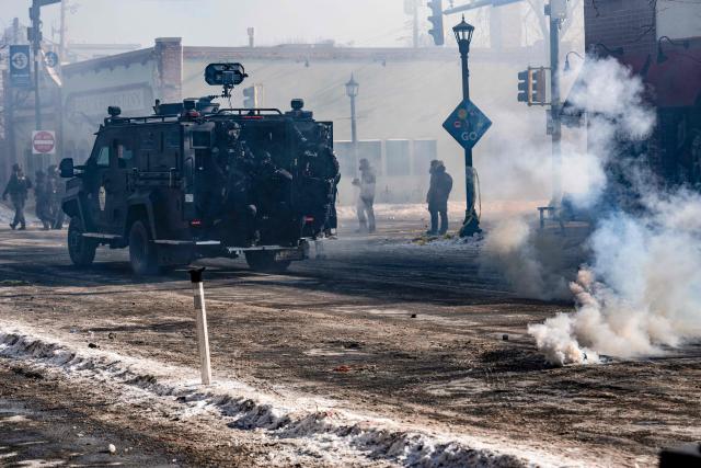 Minneapolis police officers ride an armored vehicle after releasing gas canisters at protesters near where a man was shot dead by federal immigration agents in Minneapolis, Minnesota, on January 24, 2026. Federal immigration agents shot dead a man in Minneapolis on Saturday, officials said -- the second fatal shooting of a civilian in the city, sparking fresh protests and outrage from state officials. The death came less than three weeks after US citizen Renee Good was shot and killed by an Immigration and Customs Enforcement officer involved in sweeps to round up undocumented migrants. (Photo by ROBERTO SCHMIDT / AFP)