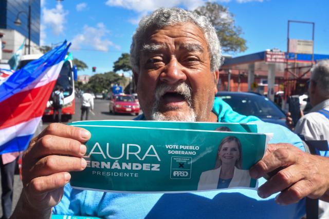 A supporter of Costa Rica's presidential candidate of the Sovereign People party, Laura Fernandez, shows a flyer during her closing campaign rally at the Colon Avenue in San Jose on January 24, 2026. Right-wing politician Laura Fernandez appears set to win Costa Rica's presidential election in the first round, according to two opinion polls published on January 21. (Photo by Ezequiel BECERRA / AFP)