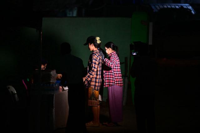 Voters (C) arrive before dawn at a polling station for the third and final phase of Myanmar's general election in Yangon on January 25, 2026. (Photo by Sai Aung MAIN / AFP)