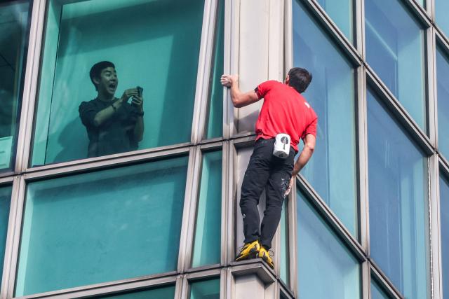 A building occupant uses his phone to record US rock climber Alex Honnold climbing the Taipei 101 building without ropes or safety gear in Taipei on January 25, 2026. (Photo by I-Hwa Cheng / AFP)