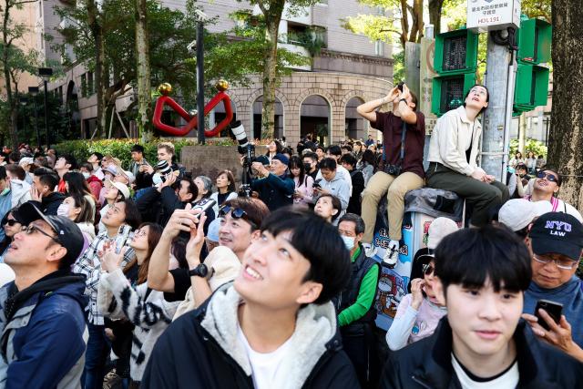 People watch US rock climber Alex Honnold scale the Taipei 101 building without ropes or safety gear in Taipei on January 25, 2026. (Photo by I-Hwa Cheng / AFP)