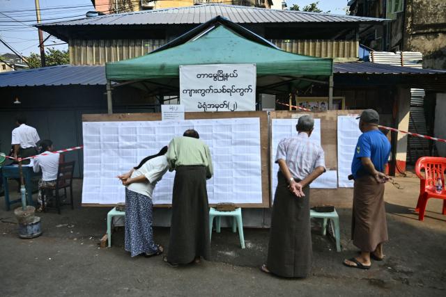 People check a voter list at outside of a polling station during the third and final phase of Myanmar's general election in Yangon on January 25, 2026. Myanmar opened the final round of its month-long election on January 25, with the dominant pro-military party on course for a landslide in a junta-run vote critics say will prolong the army's grip on power. (Photo by Sai Aung MAIN / AFP)