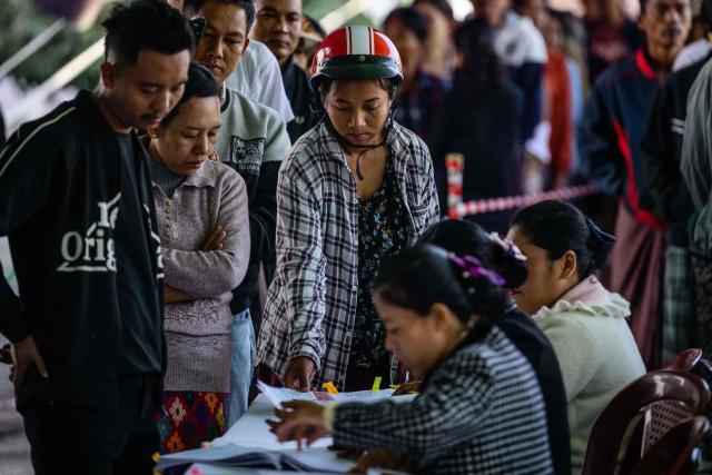 People line up to check a voter list before casting their ballots at a polling station during the third and final phase of Myanmar's general election in Mandalay on January 25, 2026. Myanmar opened the final round of its month-long election on January 25, with the dominant pro-military party on course for a landslide in a junta-run vote critics say will prolong the army's grip on power. (Photo by ANTHONY WALLACE / AFP)