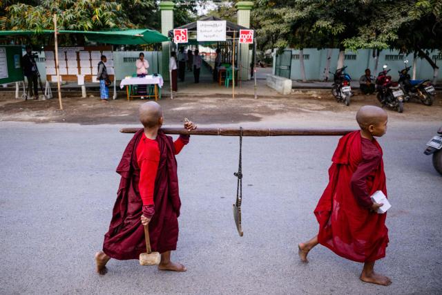 Novice monks walk past a polling station (back) during the third and final phase of Myanmar's general election in Mandalay on January 25, 2026. Myanmar opened the final round of its month-long election on January 25, with the dominant pro-military party on course for a landslide in a junta-run vote critics say will prolong the army's grip on power. (Photo by ANTHONY WALLACE / AFP)