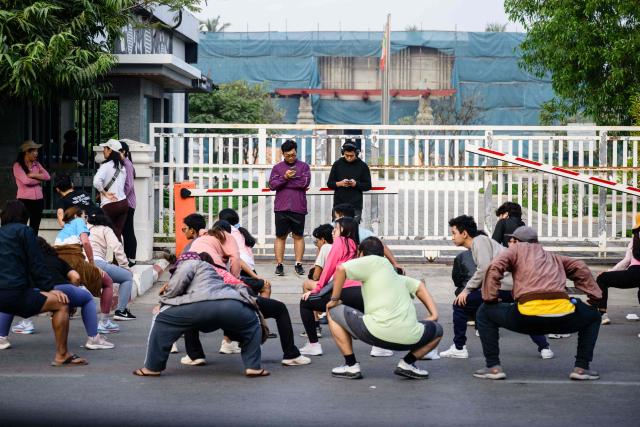 People exercise along a roadside in Mandalay on January 25, 2026. (Photo by ANTHONY WALLACE / AFP)