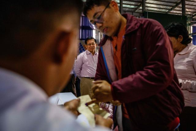 Military chief Min Aung Hlaing (back C) watches a voter ink their finger as he visits a polling station during the third and final phase of Myanmar's general election in Mandalay on January 25, 2026. (Photo by ANTHONY WALLACE / AFP)