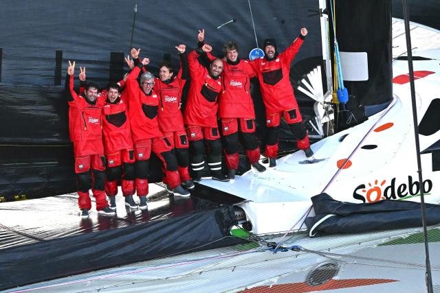 French skipper Thomas Coville (R) and his crew members celebrate aboard the Ultim class multihull "Sodebo Ultim 3" as they arrive at the end of their Jules Verne Trophy attempt, in the Atlantic Ocean, off the coast of Brest, Brittany, western France, on January 25, 2026. Thomas Coville (Sodebo) and his six crew members completed a non-stop round-the-world voyage off the coast of Brest on January 25, 2026 in a record time of 40 days, 10 hours and 45 minutes, beating the previous Jules Verne Trophy record by 12 hours, his team announced. The Jules Verne Trophy is a prize for the fastest crewed, unassisted and non-stop circumnavigation of the world on any type of yacht. (Photo by LOIC VENANCE / AFP)