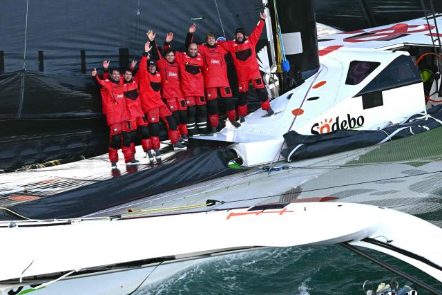 French skipper Thomas Coville (R) and his crew members celebrate aboard the Ultim class multihull "Sodebo Ultim 3" as they arrive at the end of their Jules Verne Trophy attempt, in the Atlantic Ocean, off the coast of Brest, Brittany, western France, on January 25, 2026. Thomas Coville (Sodebo) and his six crew members completed a non-stop round-the-world voyage off the coast of Brest on January 25, 2026 in a record time of 40 days, 10 hours and 45 minutes, beating the previous Jules Verne Trophy record by 12 hours, his team announced. The Jules Verne Trophy is a prize for the fastest crewed, unassisted and non-stop circumnavigation of the world on any type of yacht. (Photo by LOIC VENANCE / AFP)