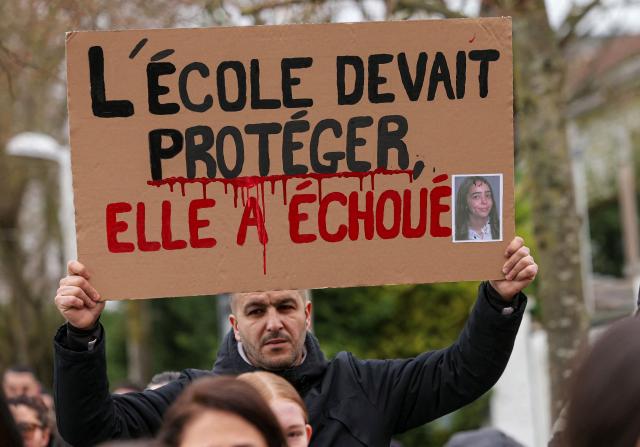 A mourner holds a placard reading "The school was supposed to protect, but it failed" during a silent march for 17-year-old girl Camelia, a high school student who committed suicide at Mitry-Mory station following school harassment, in Mitry-Mory on January 25, 2026. The family of 17-year-old high school student Camelia, who committed suicide in Mitry-Mory (Seine-et-Marne), has filed a complaint and will soon be heard as part of the investigations opened after the teenager's death, the Meaux public prosecutor said. On January 14, 2026 the day after the teenager's death, two investigations were opened, one of which was for ‘bullying at school leading to the victim's suicide’. (Photo by Thomas SAMSON / AFP)