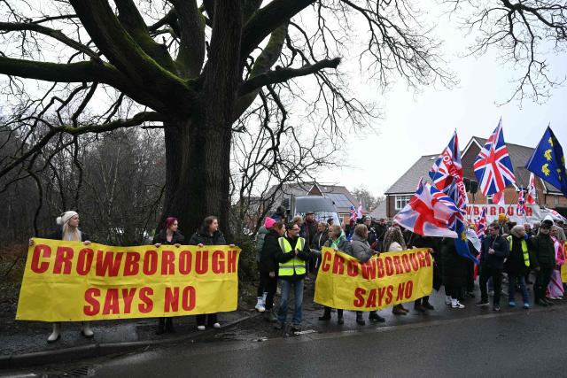 Protesters stand with signs saying "Crowborough Says 'No'" near to the entrance to the Crowborough Training Camp, a former military site, in Crowborough, south-east England on January 25, 2026, during a protest calling for the barracks not to be used to house asylum seekers. Britain's government confirmed on January 22, that the first 27 illegal migrants had been moved into the Crowborough military barracks in East Sussex, which will eventually house more than 500 illegal migrants. (Photo by JUSTIN TALLIS / AFP)