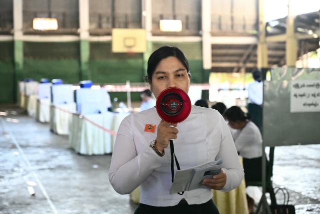 A member of Myanmar’s Union Election commission (UEC) announces the closing of polls at a polling station in the third phase of Myanmar’s general election in Yangon on January 25, 2026. (Photo by Sai Aung MAIN / AFP)