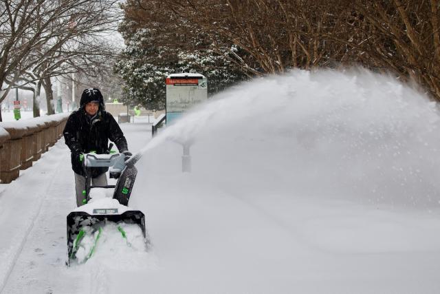 A worker clears a sidewalk near the National Mall as snow falls in Washington, DC, on January 25, 2026. A massive winter storm on January 24 dumped snow and freezing rain from New Mexico to North Carolina as it swept across the United States towards the northeast, threatening tens of millions of Americans with blackouts, transportation chaos and bone-chilling cold. After battering the country's southwest and central areas, the storm system began to hit the heavily populated mid-Atlantic and northeastern states as a frigid air mass settled in across the nation. (Photo by Amid FARAHI / AFP)