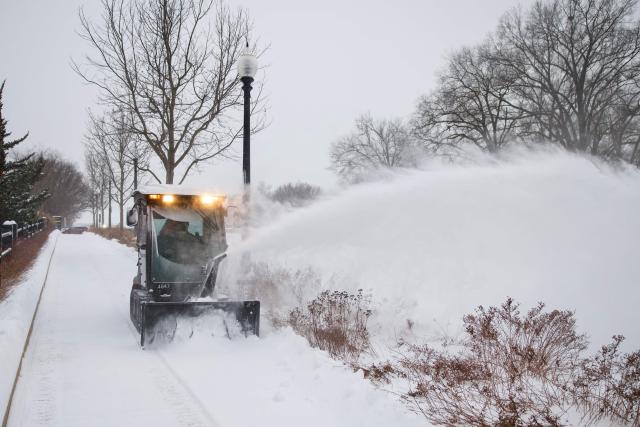 A worker clears a sidewalk near the National Mall as snow falls in Washington, DC, on January 25, 2026. A massive winter storm on January 24 dumped snow and freezing rain from New Mexico to North Carolina as it swept across the United States towards the northeast, threatening tens of millions of Americans with blackouts, transportation chaos and bone-chilling cold. After battering the country's southwest and central areas, the storm system began to hit the heavily populated mid-Atlantic and northeastern states as a frigid air mass settled in across the nation. (Photo by Amid FARAHI / AFP)