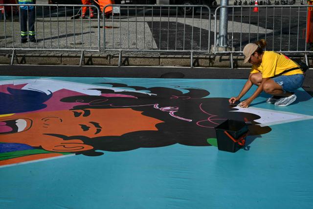 An artist paints a large canvas banner depicting one of the host cities of the Women’s World Cup at Avenida Atlantica on the seaside promenade of the iconic Copacabana beach, during the Street Art Festival within the launch of the 2027 FIFA Women's World Cup in Rio de Janeiro, Brazil on January 25, 2026. (Photo by Pablo PORCIUNCULA / AFP)